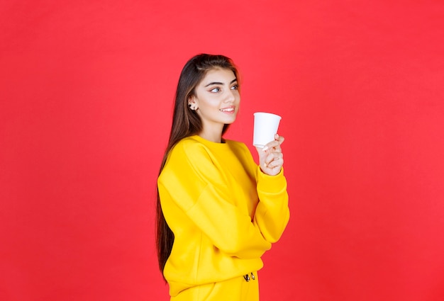 Porträt einer schönen Frau im gelben Outfit, die mit einer Tasse Tee posiert
