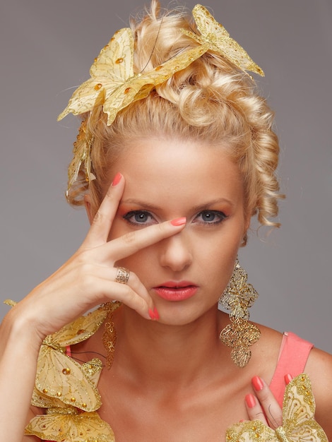 Kostenloses Foto porträt einer schönen frau mit goldenen schmetterlingen im dekor. isoliert auf grauem hintergrund