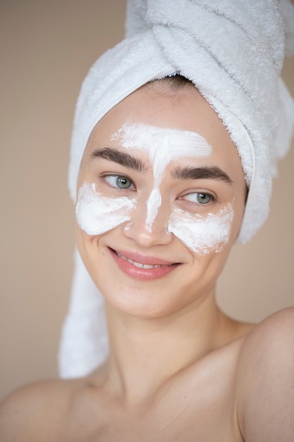 Porträt einer schönen Frau mit klarer Haut, die Feuchtigkeitscreme im Gesicht verwendet