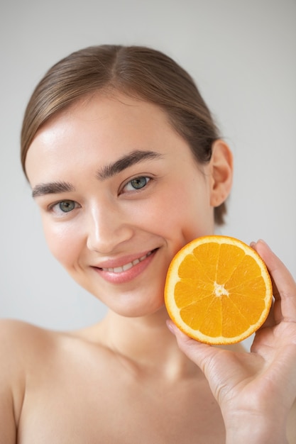 Porträt einer schönen Frau mit klarer Haut, die in Scheiben geschnittene Orangenfrüchte hält