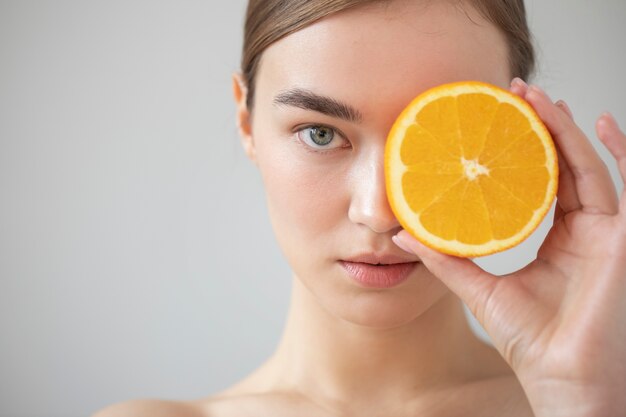 Porträt einer schönen Frau mit klarer Haut, die in Scheiben geschnittene Orangenfrüchte hält