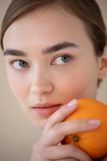 Porträt einer schönen Frau mit klarer Haut, die Orangenfrüchte hält