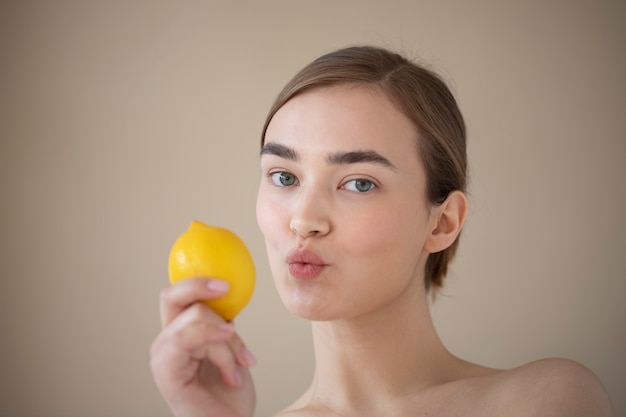 Porträt einer schönen Frau mit klarer Haut, die Zitronenfrucht hält