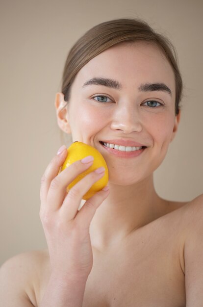 Porträt einer schönen Frau mit klarer Haut, die Zitronenfrucht hält