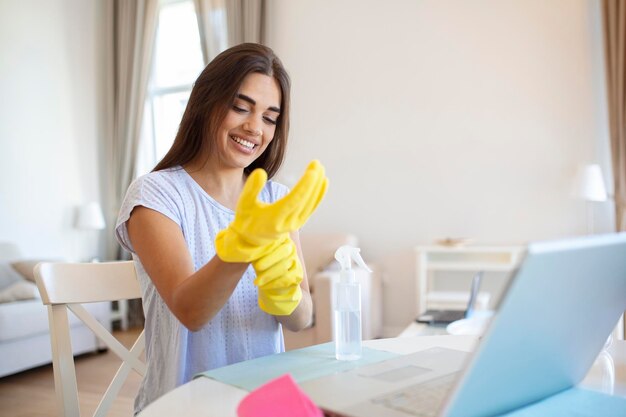 Porträt einer schönen Hausfrau, die gelbe Schutzhandschuhe anzieht Frau glückliches Reinigungskonzept