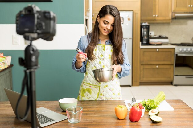 Porträt einer schönen jungen Food-Bloggerin, die zu Hause etwas zu essen zubereitet und ein Video aufnimmt