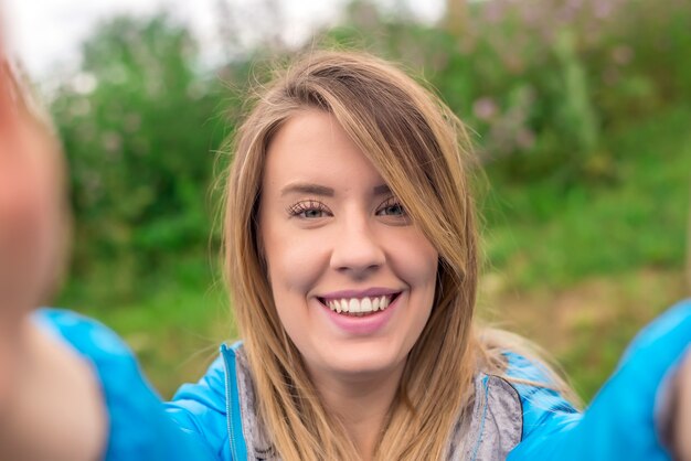 Porträt einer schönen jungen Frau selfie im Park mit einem Smartphone. Portrait einer fröhlichen Frau, die Selbstfoto macht