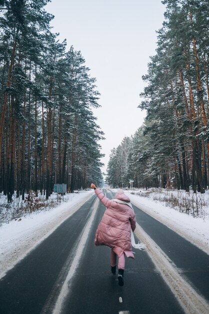 Porträt einer schönen kaukasischen Frau auf einer Straße durch verschneiten Wald