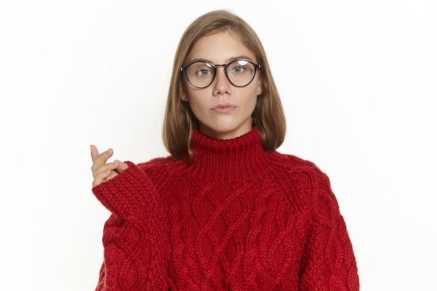 Kostenloses Foto porträt einer schönen langhaarigen jungen frau in brille und kastanienbraunem pullover, die verwirrten gesichtsausdruck verwirrt, geste macht, über etwas nachdenkt, schaut