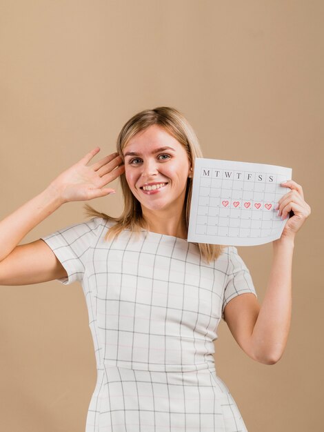 Porträt einer smileyfrau, die den Zeitraumkalender hält