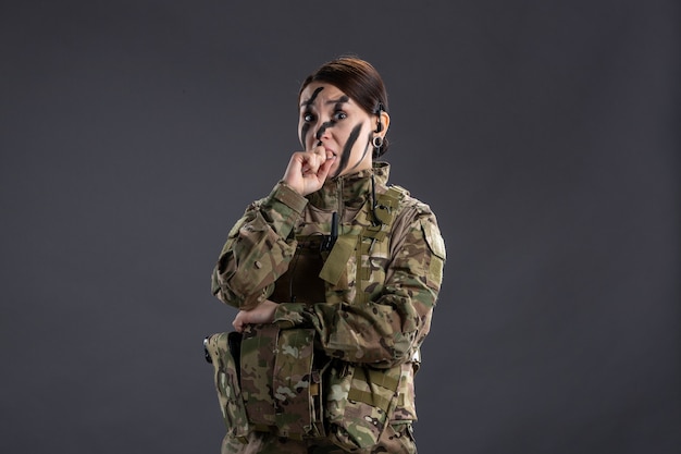 Porträt einer Soldatin in Tarnung an der dunklen Wand