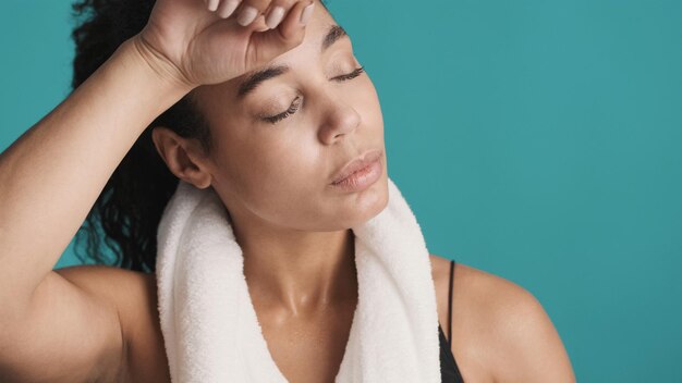 Porträt einer sportlichen Afro-Frau, die sich nach einem harten Training über buntem Hintergrund die Stirn wischt Sportliches Mädchen