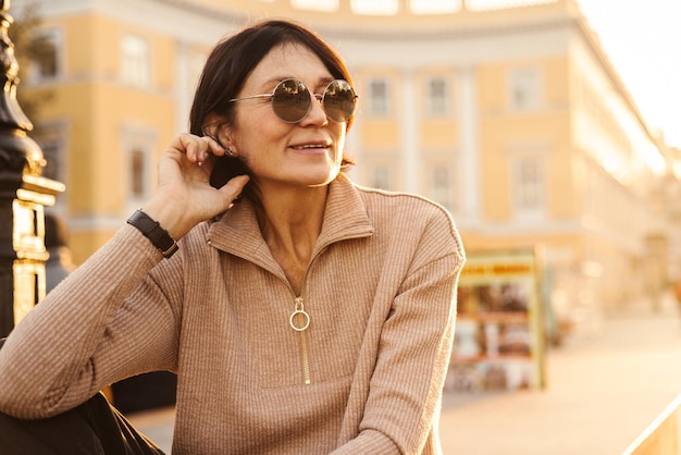 Porträt einer süßen, hellhäutigen erwachsenen Frau, die an einem sonnigen Frühlingstag im Freien auf einem Platz sitzt Freizeit-Lifestyle- und Beauty-Konzept