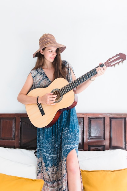 Kostenloses Foto porträt einer talentierten jugendlichen, die auf dem bett spielt gitarre steht