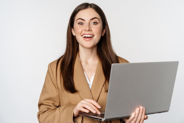 Porträt einer Unternehmensfrau, die mit einem Laptop arbeitet, der lächelnd und selbstbewusst auf weißem Hintergrund aussieht