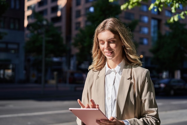 Porträt einer Unternehmensfrau, die mit ihrem digitalen Tablet arbeitet und auf der Straße geht, um ins Büro zu gehen m