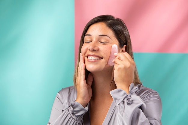 Porträt einer wunderschönen Frau, die ihr Gesicht mit einem Gua sha . massiert