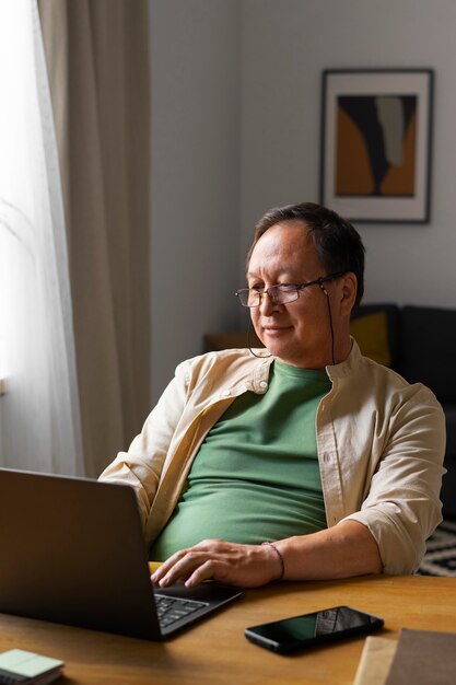 Porträt eines älteren Mannes, der zu Hause einen Laptop benutzt