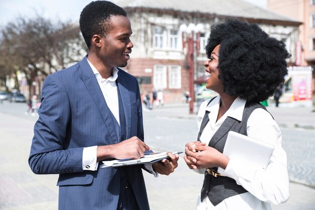 Porträt eines afrikanischen jungen Geschäftsmannes und der Geschäftsfrau, die miteinander in der Stadt sprechen