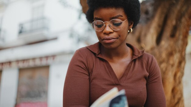 Porträt eines afroamerikanischen Mädchens mit Brille, das Zeit zum Lesen hat