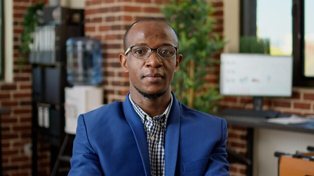 Porträt eines afroamerikanischen Mitarbeiters, der E-Mails auf einem Laptop beantwortet und an einem Website-Bericht arbeitet. Bürounternehmer, der Papierkram-Recherche auf dem Computer analysiert, Internet-Recherche durchführt.