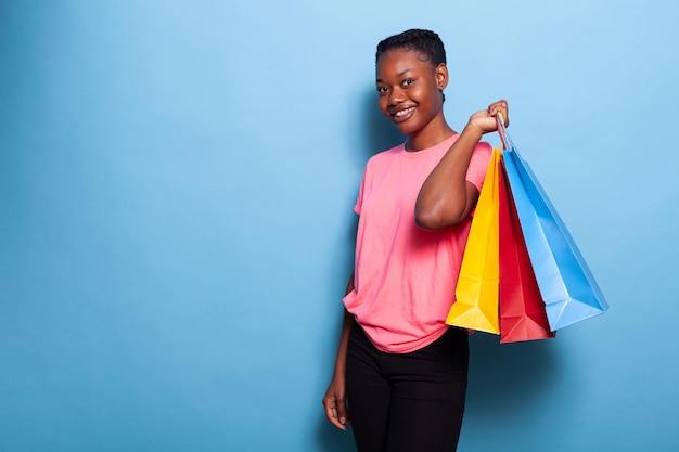 Porträt eines afroamerikanischen Teenagers, der Einkaufstüten aus Papier hält und Geschenke kauft
