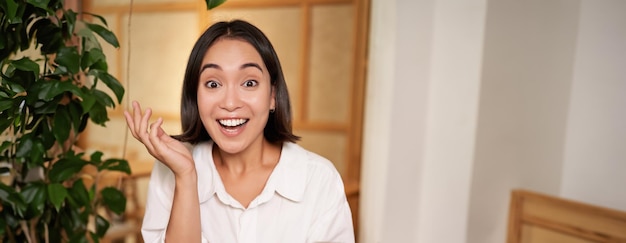 Porträt eines asiatischen Mädchens, das überrascht aussieht und sein Mobiltelefon mit erstauntem Gesicht in der Hand hält. Tolle Neuigkeiten