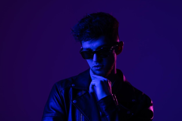 Porträt eines attraktiven Mannes mit Brille, der weit weg schaut, isoliert über dunklem, neonviolettem Hintergrund