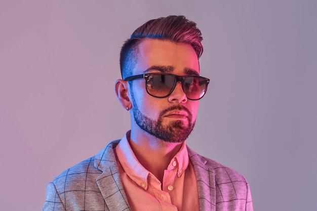 Porträt eines attraktiven, nachdenklichen Mannes in kariertem Blazer und Sonnenbrille. Rote und blaue Lichter.