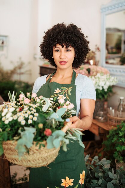 Porträt eines attraktiven weiblichen Floristen, der Korb von Blumen hält