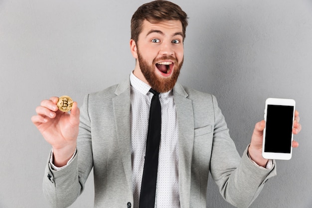 Porträt eines aufgeregten Geschäftsmannes, der bitcoin hält
