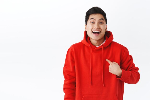 Porträt eines aufgeregten, glücklich lächelnden Mannes in rotem Hoodie, der auf sich selbst als ausgewählt oder ausgewählt zeigt, Ziel erreichen