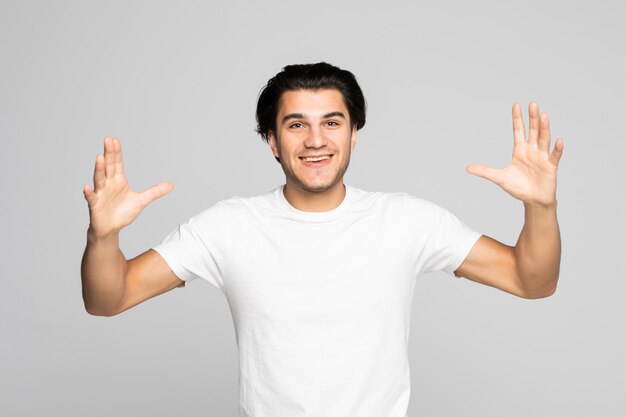 Porträt eines aufgeregten zufälligen Mannes, der mit erhobenen Händen auf Weiß steht