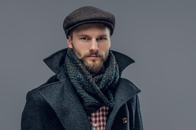 Porträt eines bärtigen Hipster-Mannes in grauer Jacke und Wollmütze isoliert auf grauem Hintergrund.