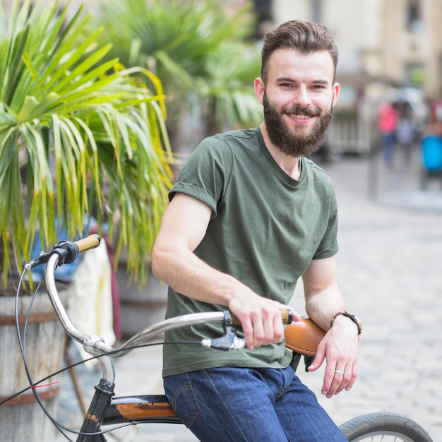 Porträt eines bärtigen jungen männlichen Radfahrers, der auf Fahrrad sitzt