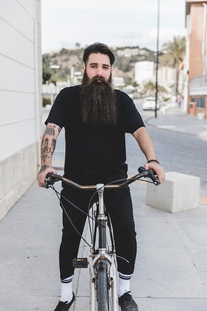 Porträt eines bärtigen jungen Mannes, der auf Fahrrad sitzt