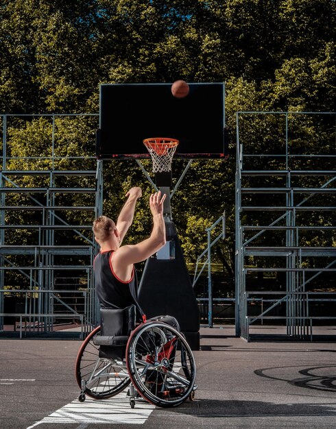 Porträt eines behinderten Basketballspielers im Rollstuhl auf einem offenen Spielfeld.