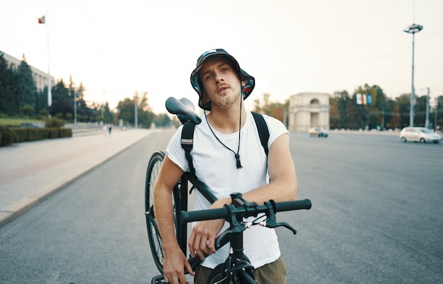 Porträt eines blonden weißen Mannes in der Stadt mit einem klassischen Fahrrad