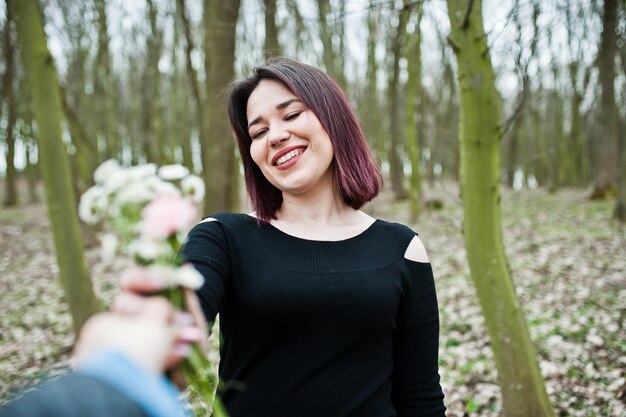 Porträt eines brünetten Mädchens im schwarzen Kleid am Frühlingsholz