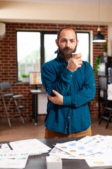 Porträt eines buchhalters mit einer tasse kaffee, der im büro eines startup-unternehmens steht und geschäftsdokumente analysiert, die an einer marketingpräsentation arbeiten. executive manager plant finanzstrategie