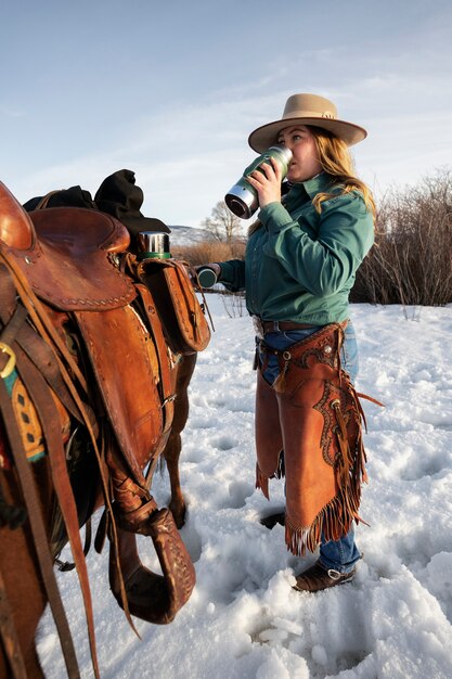 Porträt eines Cowgirls, das neben einem Pferd trinkt