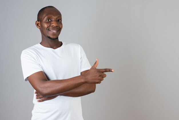 Porträt eines dunkelhäutigen Mannes im weißen T-Shirt, der auf grauer Wand steht