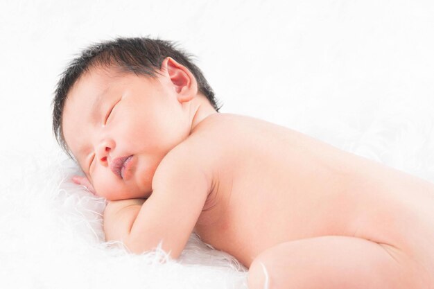 Porträt eines einen monat alten schlafenden, neugeborenen mädchens auf einer weißen decke. konzept portrait studio mode neugeborenes.