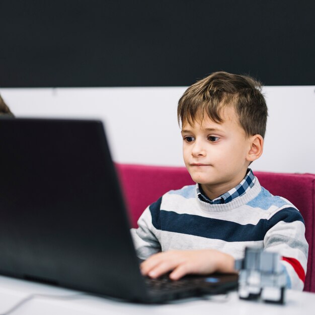 Porträt eines ernsten Jungen, der Laptop im Klassenzimmer verwendet