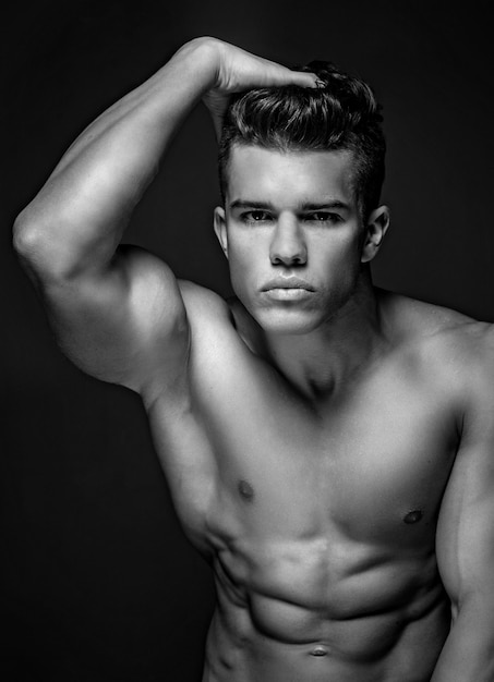 Porträt eines fantastischen männlichen Modells mit nacktem muskulösen Körper. Isoliert auf dunkelgrauem Hintergrund.