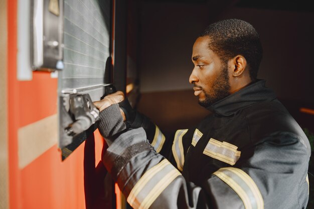 Kostenloses Foto porträt eines feuerwehrmanns, der vor einem feuerwehrauto steht