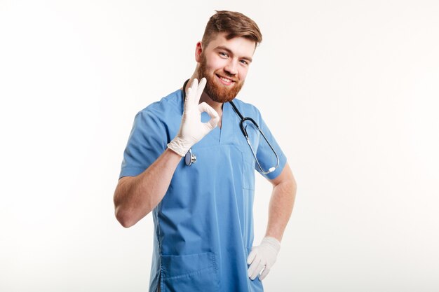 Porträt eines freundlichen glücklichen männlichen Arztes, der ok Geste zeigt