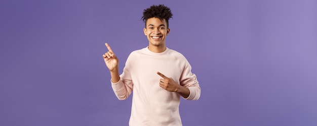Porträt eines fröhlichen, gesunden, lächelnden Mannes, der mit dem Finger in die obere linke Ecke zeigt und den Kauf eines Produkts empfiehlt