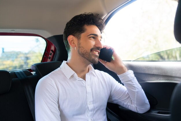 Porträt eines Geschäftsmannes, der auf dem Weg zur Arbeit in einem Auto telefoniert?