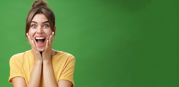 Kostenloses Foto porträt eines glücklichen, entzückten und überraschten jungen weiblichen mädchens in gelbem t-shirt, das die hände zu